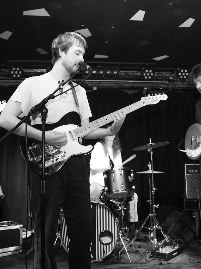two male band members perform on stage with guitars