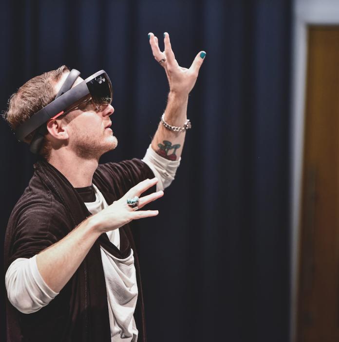 A white man wearing a VR headset with hands in the air.