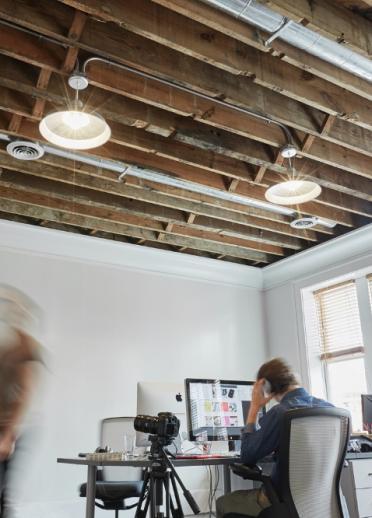 Busy office with white walls and wooden beams on the ceiling.