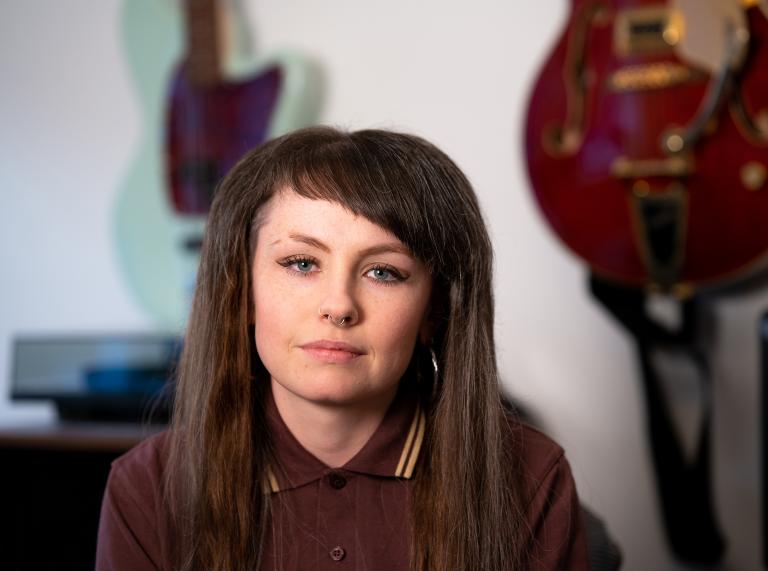Close up shot of soul singer Nia Wyn. Nia wears a burgundy polo shirt and has long brown hair with a side fringe. 