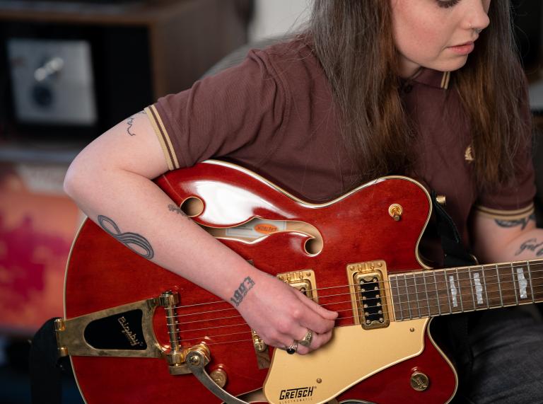 Close up shot of Nia Wyn playing a red semi-acoustic gretsch streamliner.