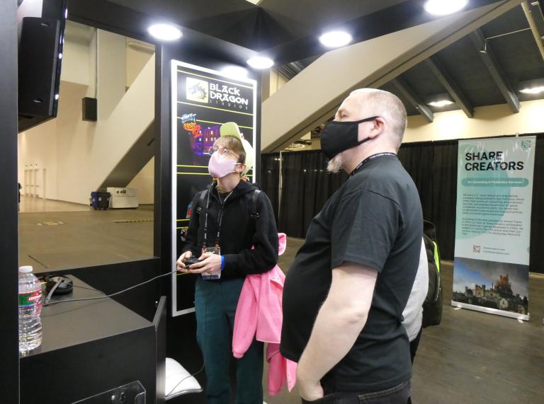 Two people dressed all in black viewing a screen at the Games Developer Conference