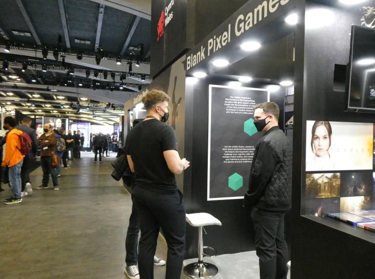 Two people dressed in black talking in front of a black display at the Games Developer Conference