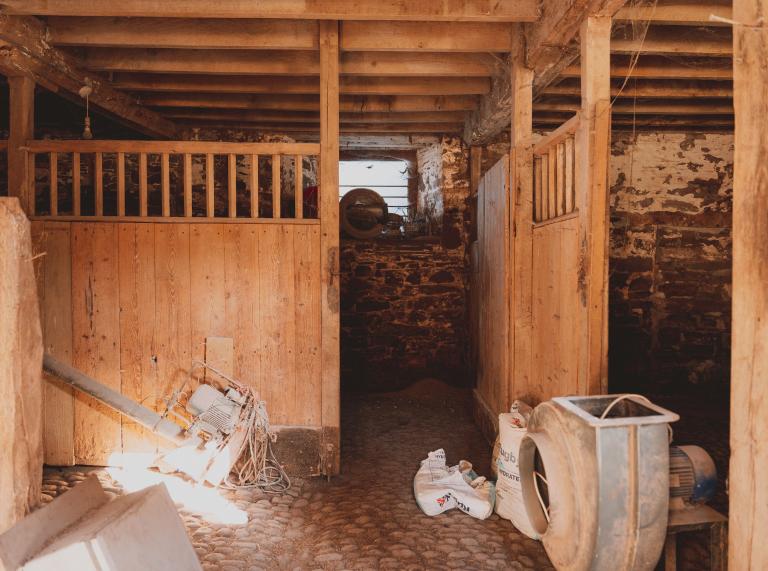 A stable with farming equipment inside