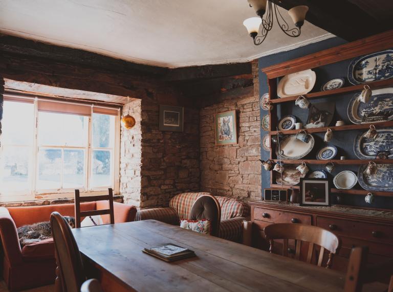 A cosy farmhouse dining room filled with hanging crockery and wooden furniture
