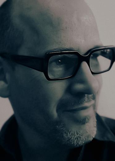 Close up shot of Will Julien-Morris. He is wearing thick black glasses and a black shirt.
