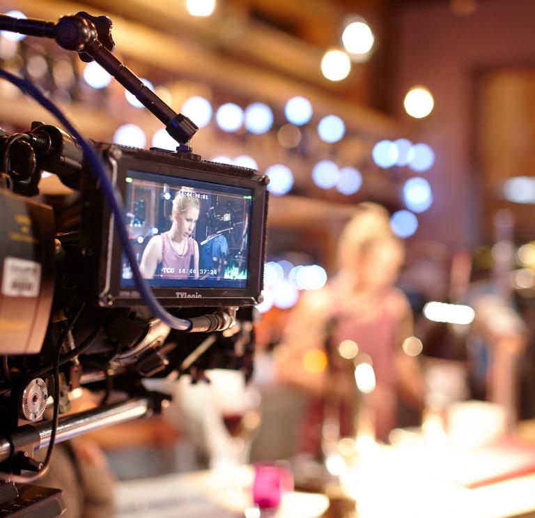 Close up of small camera screen showing image of person on set in background