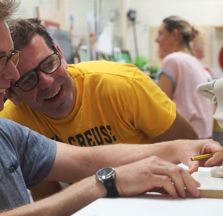 Close up of two people making characters out of clay 