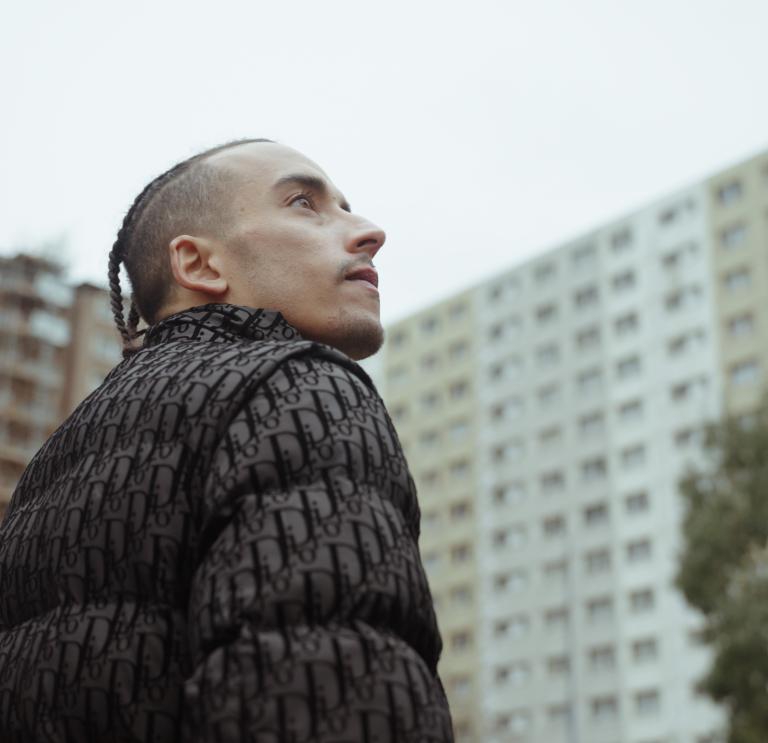 A person wearing a black jacket stares up to the sky.