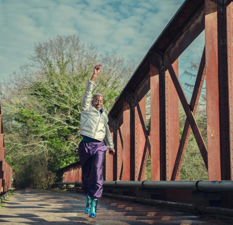Sex Education cast member jumps up as he crosses a bridge in a scene from Sex Education