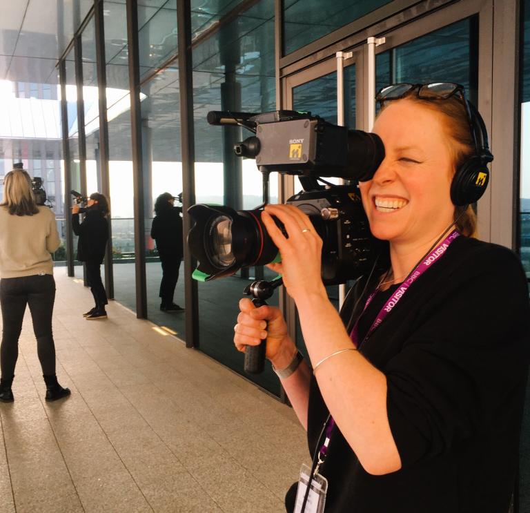 Female holding a camera, practicing her videography skills