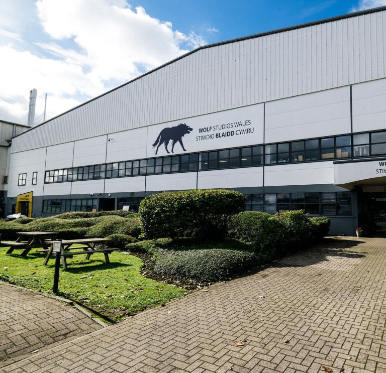 Exterior view of a film and TV studio, a large white building with  Black Wolf logo and a sign that says
