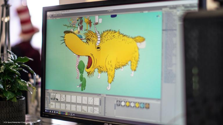 Computer screen with an artist drawing a yellow four-legged animal from Dr Seuss