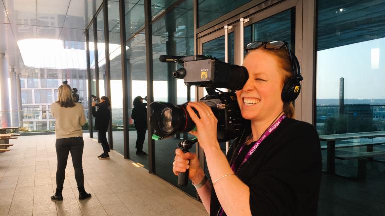 Female holding a camera, practicing her videography skills