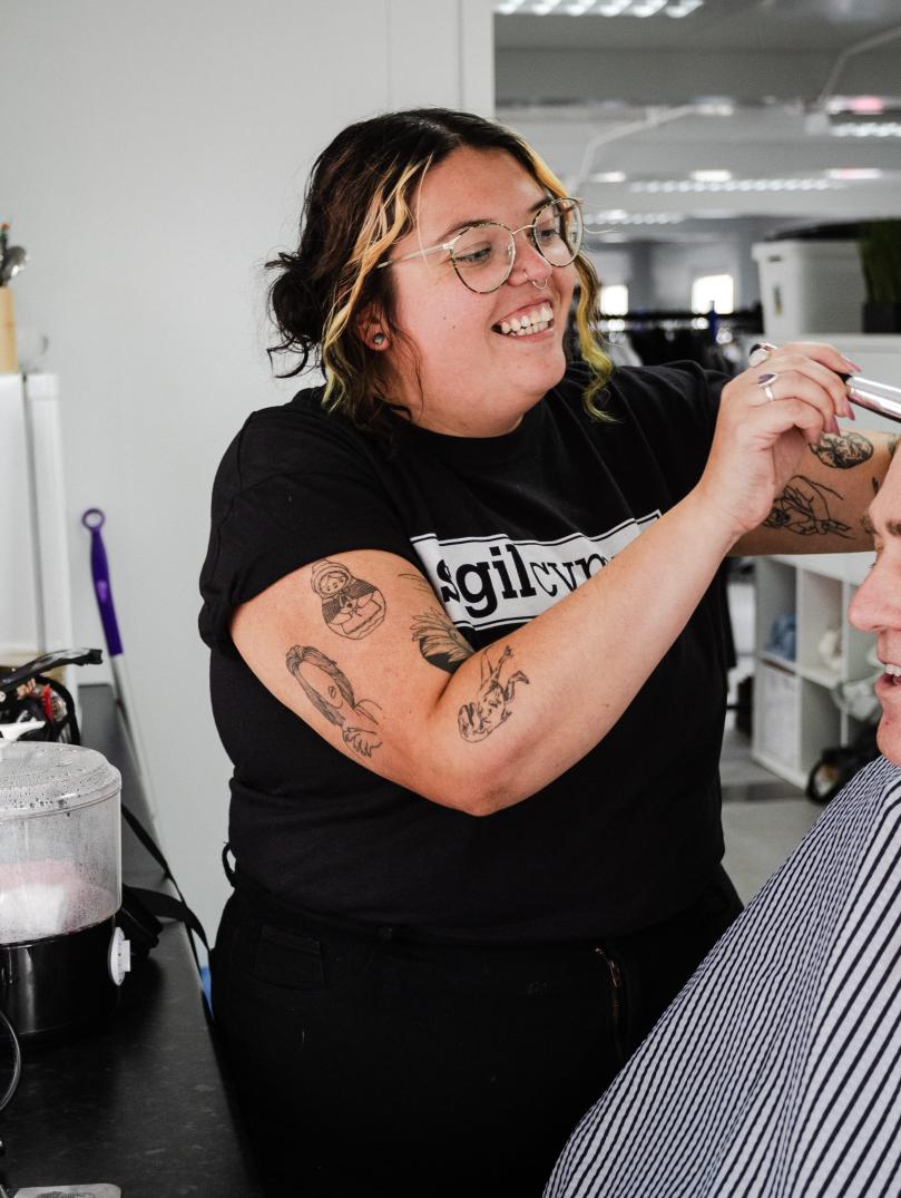 Trainee Fiorella Wyn, smiles as she is doing make up on a male participant back stage