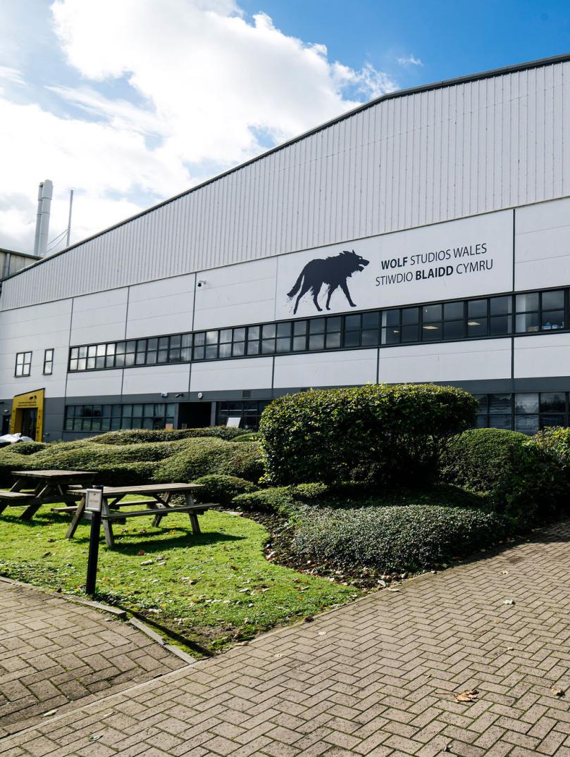 Exterior view of a film and TV studio, a large white building with  Black Wolf logo and a sign that says