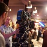 Over the shoulder shot of a person operating a big TV camera in a studio