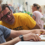 Close up of two people making characters out of clay 
