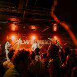 A busy crowd under red lights at a Buzzard Buzzard Buzzard gig at Clwb Ifor Bach