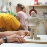 Close up of two people making characters out of clay 