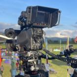 Close up shot of person wearing headphones operating a film camera on location in countryside.  