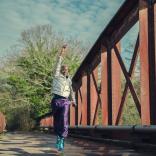 Sex Education cast member jumps up as he crosses a bridge in a scene from Sex Education