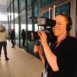 Female holding a camera, practicing her videography skills