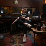white man sits in recording studio with equipment in the background