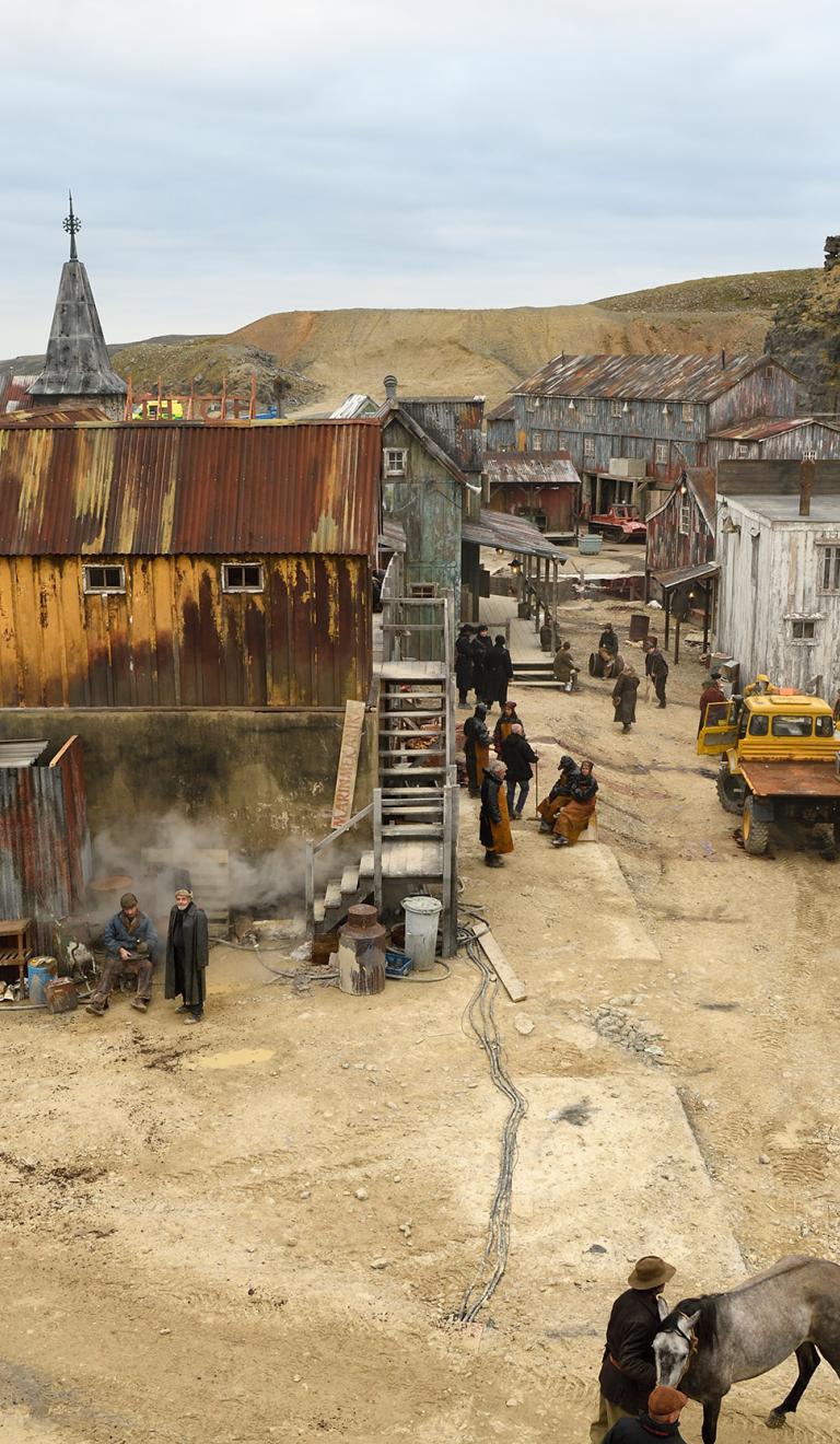 Filming location depicting a town set with metal houses and huts against a quarry backdrop